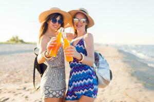 bellissimo ragazze godendo loro cocktail nel bottiglie su soleggiato estate sorprendente California spiaggia. messa a fuoco su bevande. foto