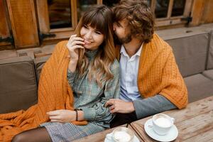 romantico momenti. chilling coppia nel amore seduta su terrazza e potabile mattina caffè e godendo prima colazione. uomo e donna coperto di lenzuolo. foto