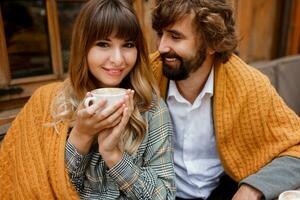 vicino su accogliente caldo ritratto di contento abbracciare coppia nel amore. bello uomo e bella donna avendo prima colazione e potabile caffè su terrazza. foto