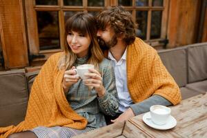 romantico momenti. chilling coppia nel amore seduta su terrazza e potabile mattina caffè e godendo prima colazione. uomo e donna coperto di lenzuolo. foto