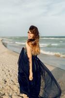 all'uscita grazioso donna nel elegante lungo blu vestito Ingannare in giro e avendo divertimento su il tropicale spiaggia. vacanza tempo foto