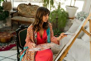 femmina artista pittura su tela nel sua arte studio. indossare elegante boho vestito. foto