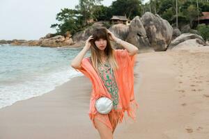 bellissimo donna con lungo capelli nel elegante boho estate vestito in posa su il tropicale spiaggia. foto