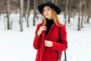 all'aperto moda ritratto di fascino l giovane allegro elegante signora indossare di moda inverno attrezzatura , nero lana cappello e rosso cappotto . freddo stagione.bionda lungo capelli. pieno labbra, blu occhi. foto