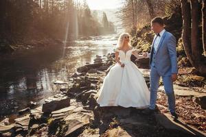 sposi che si tengono per mano sullo sfondo dei fiumi nei tramonti foto