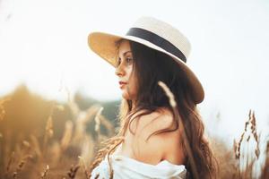 bella donna con un cappello tra l'erba del campo foto