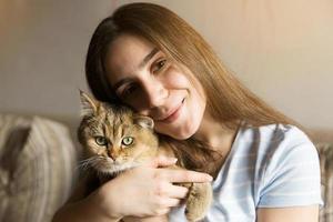 ragazza carina seduta che abbraccia un gatto foto