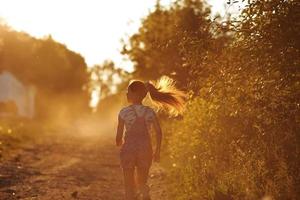 ragazza felice che corre lungo una strada di campagna foto