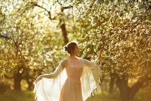 donna in un vestito vicino a un melo in fiore