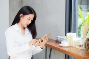 giovane donna asiatica che utilizza computer tablet nella caffetteria. foto