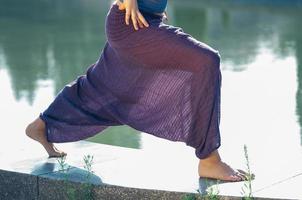 donna attraente in pantaloni viola che pratica asana yoga all'aperto foto