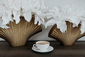 un' avvicinamento di bianca porcellana caffè tazza su un' di legno tavolo nel a casa. moderno interno design. cappuccino con cioccolato su il tavolo. caldo caffè bevanda concetto. foto