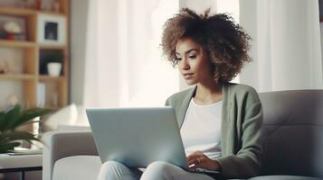 bellissimo africano americano donna seduta a casa su il divano con un' il computer portatile. donna studiando in linea o Lavorando. ai generativo foto