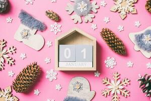 superiore Visualizza di di legno calendario, vacanza giocattoli e decorazioni su rosa Natale sfondo. il primo di gennaio. nuovo anno tempo concetto foto