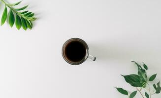 creativo disposizione fatto di verde le foglie e caffè tazza su bianca sfondo. piatto posizione, superiore Visualizza. foto