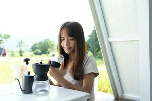 asiatico femmina turista macinare e infuso caffè per bevanda nel il mattina. foto