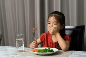 poco carino ragazzo ragazza rifiuto per mangiare salutare verdure. bambini fare non piace per mangiare verdure. foto