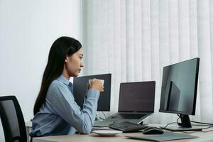 la donna asiatica stava bevendo caffè la mattina presto mentre contemplava il programma e il codice sullo schermo del computer. foto