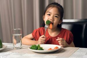 asiatico poco ragazza mangiare salutare verdure con assaporare. foto