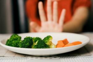 poco carino ragazzo ragazza rifiuto per mangiare salutare verdure. bambini fare non piace per mangiare verdure. foto