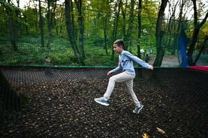 ragazzo salto su un' trampolino nel un all'aperto parco. foto