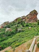 rocce e di legno recinto su un' verde pendio sotto un' nuvoloso cielo foto