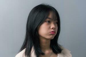 giovane bellissimo asiatico adolescenziale ragazza mostrando un' triste, deluso espressione su sfondo. foto