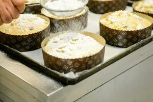 capocuoco producendo Panettone, mentre lievitare, aggiungendo mandorla zucchero guarnizione per crudo dolce pane. foto