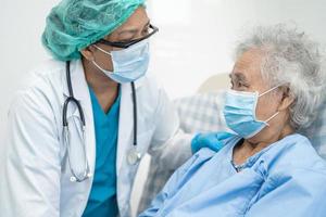 il medico aiuta il paziente anziano asiatico che indossa la maschera per proteggere il coronavirus. foto