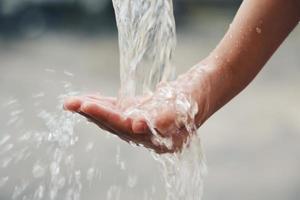 la mano cattura le gocce d'acqua che escono dal rubinetto foto