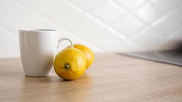 due limoni sul tavolo della cucina vicino a una tazza di tè bianca foto