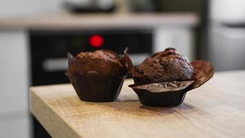 due muffin al cioccolato su un tavolo di legno contro la cucina moderna foto