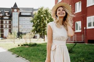 una bella bionda cammina per una città. donna in abito bianco foto