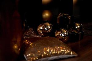 confezione regalo nera con nastro dorato e grandi palle di capodanno d'oro su fondo nero