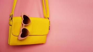 borsa gialla e occhiali da sole a forma di cuore su sfondo rosa foto