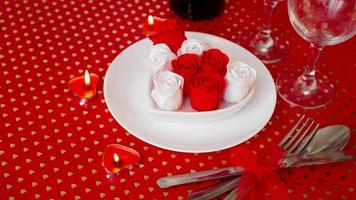 un piatto bianco con vino, coltello e forchetta su uno sfondo rosso brillante foto