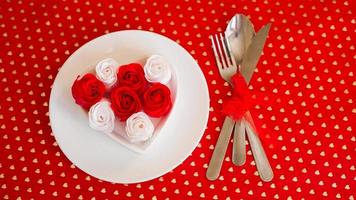 un piatto bianco con un coltello e una forchetta su uno sfondo rosso brillante foto