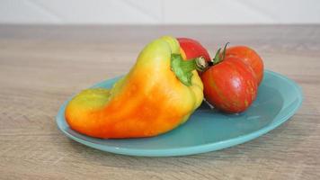 pomodoro e pepe su un piatto blu su sfondo chiaro in cucina foto