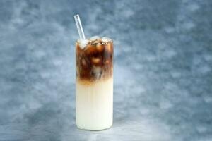 ghiaccio caffè nel alto bicchiere con bicchiere cannuccia. ghiaccio cubi e fagioli su un' rustico tavolo. foto