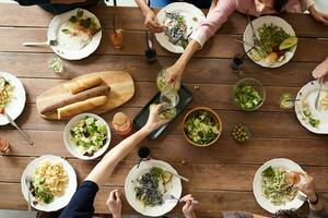 superiore Visualizza di gruppo di persone avendo cena insieme mentre seduta a di legno tavolo foto