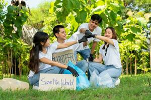 contento giovane asiatico studenti diverso volontari hold un' campagna cartello per pulizia nel il parco, il concetto di ambientale conservazione su mondo ambiente giorno, raccolta differenziata, beneficenza per sostenibilità. foto