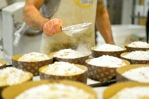 capocuoco producendo Panettone, mentre lievitare, aggiungendo mandorla zucchero guarnizione per crudo dolce pane. foto