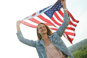una ragazza con un vestito color corallo e una giacca di jeans tiene la bandiera degli stati uniti foto