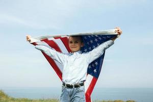 un ragazzino tiene una bandiera degli stati uniti contro il cielo foto