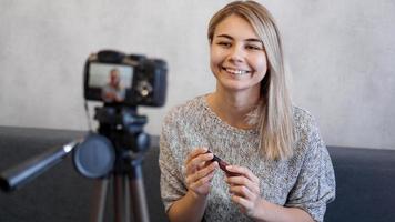 donna vlogger che mostra rossetto. blogger di bellezza in home studio foto