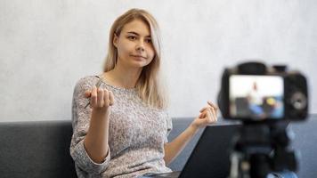 giovane blogger femminile con laptop e penna che guarda l'obbiettivo foto