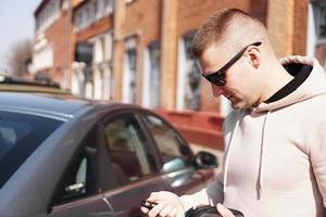 un giovane accanto alla sua auto in una giornata di sole foto