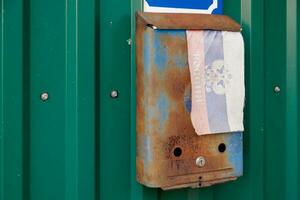 vecchio arrugginito russo cassetta postale su il parete con estremamente sbiadito piccolo tessuto russo bandiera con con cappotto di braccia foto