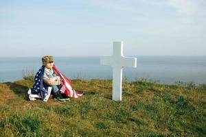 un ragazzo con un berretto militare, coperto dalla bandiera degli Stati Uniti foto