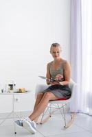 giovane donna seduta sulla sedia a casa che legge una rivista